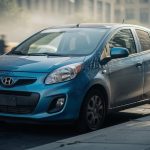 Quelle citadine hybride d’occasion choisir pour rouler en ville ? Petite voiture hybride d’occasion stationnée dans une rue urbaine, format citadin, avec circulation dense et flou d’arrière-plan.