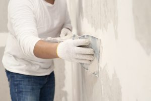 Personne appliquant une peinture sur un mur enduit à l’aide d’un rouleau.
